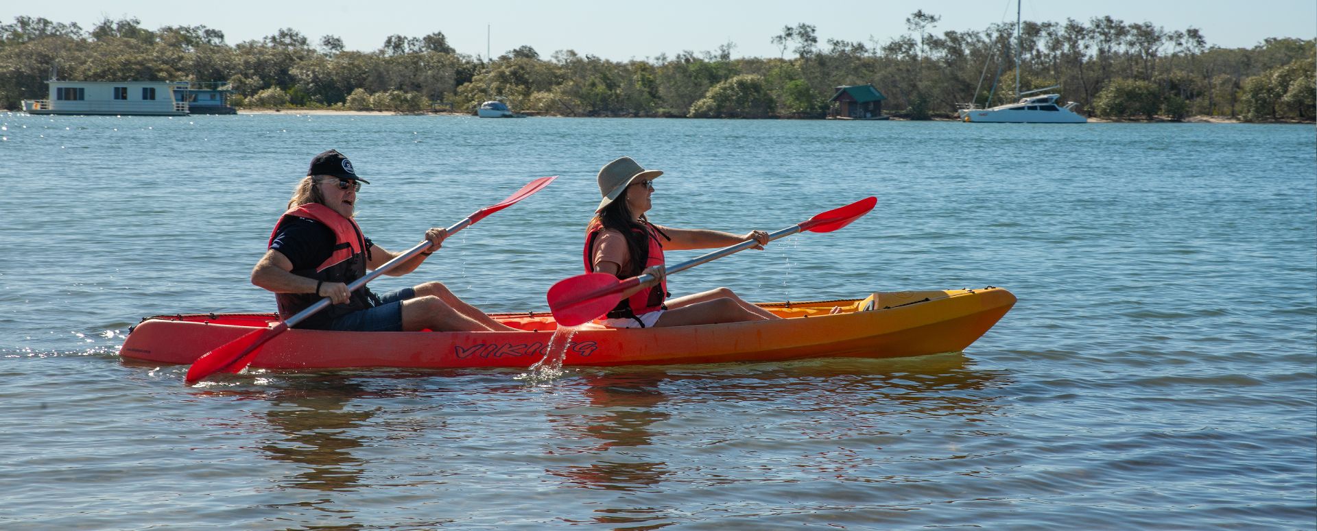 A couple using complimentary guest kayak hire to paddle along the pristine waterways of the Noosa River in Noosaville.