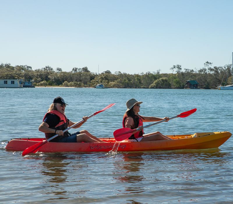 A couple paddling on the pristine waters of the Noosa River using complimentary guest kayak rentals from Cayman Quays.