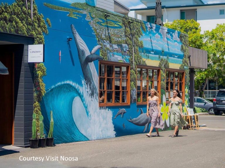 Shoppers walking by chic retail storefronts, designer labels, and local artisan shops in central downtown Noosa.