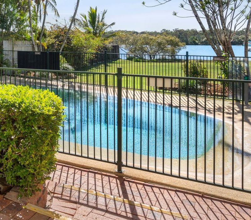 Securely fenced and gated guest swimming pool area at Cayman Quays capturing beautiful distant views of the Noosa River.