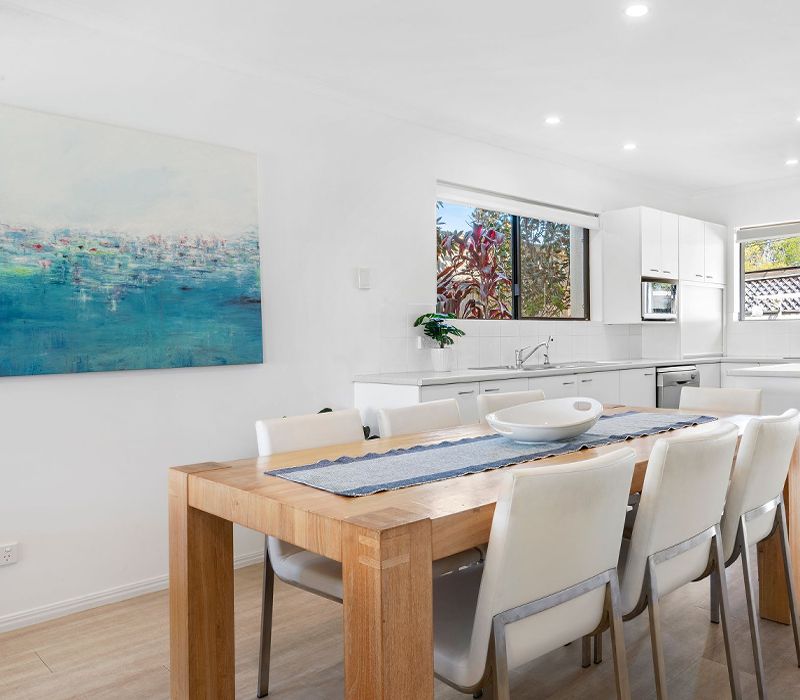 Spacious group holiday dining zone featuring a large table with seating for eight guests, situated adjacent to the fully equipped self-catering family kitchen.