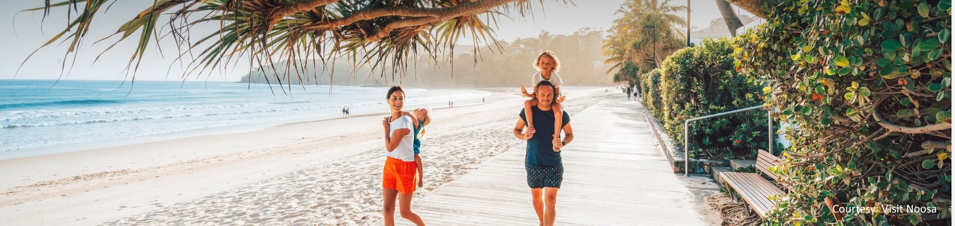 A family enjoying a scenic walk along the beachfront boardwalk and esplanade at Noosa Main Beach, located just 4km from Cayman Quays.
