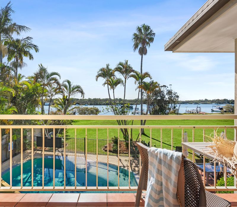 Elevated view looking down over the heated resort swimming pool and out across the beautiful Noosa River from an upper-level private apartment balcony.