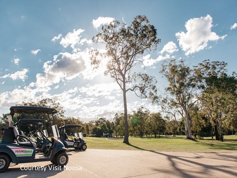 Motorized golf carts parked along the pristine, manicured fairways of a championship golf course in the Noosa region.