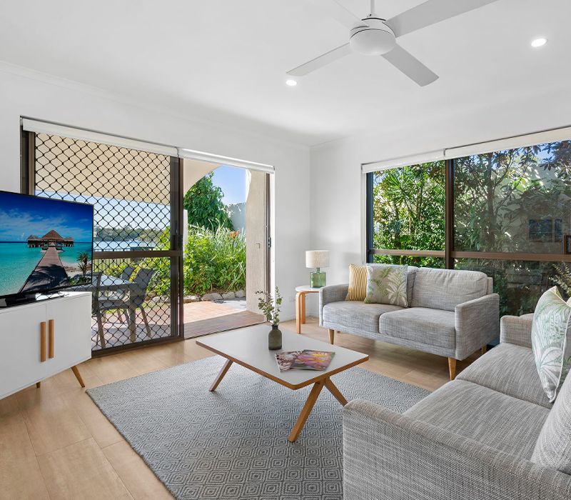 The spacious first family living area of the multi-level holiday townhouse, featuring wide doors that open up to the al fresco patio with beautiful Noosa River views.