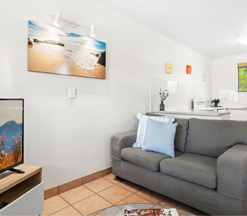 Open-plan living layout inside a Standard holiday apartment, showcasing the comfortably furnished lounge room and adjacent self-catering kitchen.