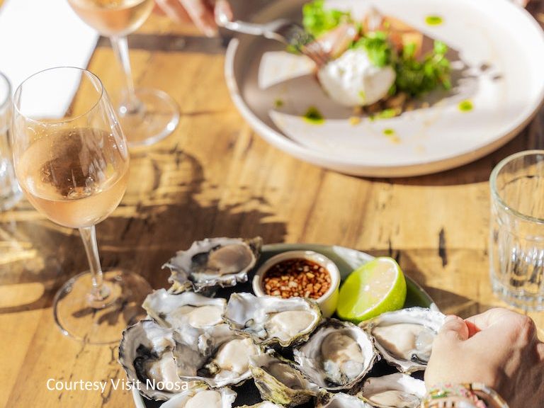 Gourmet thumbnail image showing fresh oysters served on the half shell alongside a chilled glass of white wine at a local riverside restaurant.
