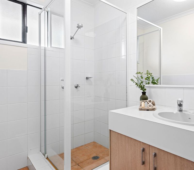 Clean and well-maintained holiday apartment bathroom facility featuring a large walk-in glass shower recess.