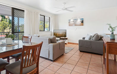 Budget-friendly Standard Apartment interior at Cayman Quays featuring a self-contained lounge zone, big screen television, and dedicated dining area.