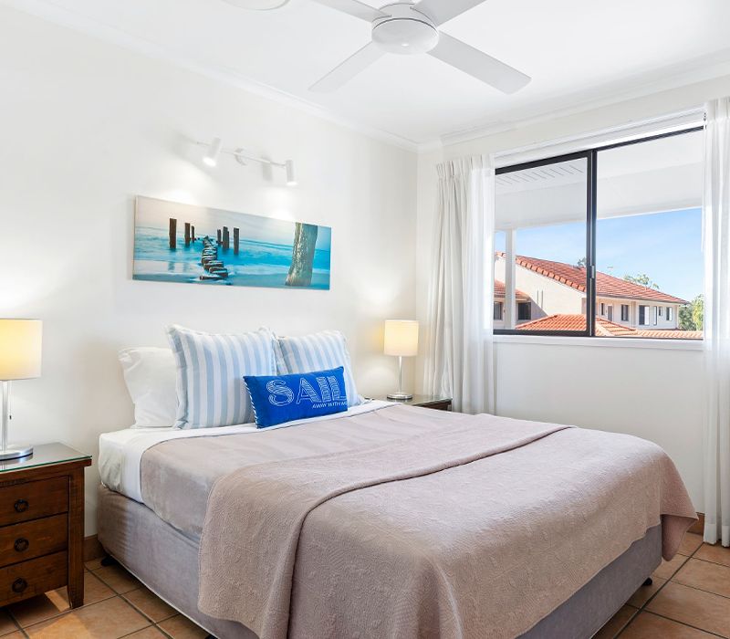 Standard Apartment master bedroom configured with a comfortable queen-size bed and a large window looking out over the resort property grounds.
