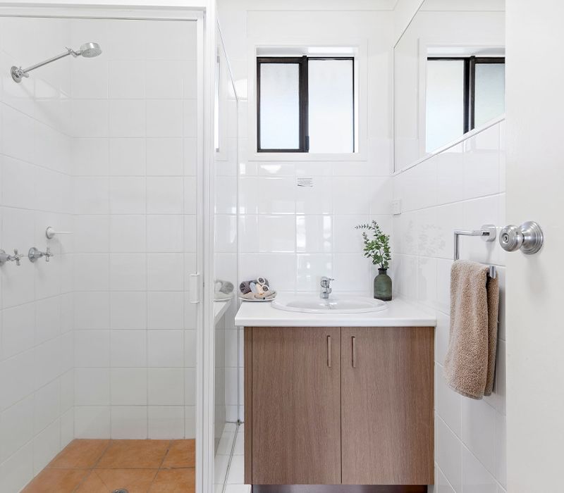 Clean and well-maintained bathroom facility inside a Standard self-contained holiday apartment at Cayman Quays, featuring a walk-in glass shower.