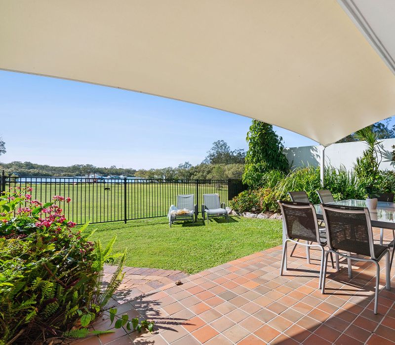 Private paved courtyard and fenced grass yard at our Noosaville family townhouse, beautifully styled with premium outdoor furniture, dining settings, and comfortable chaise sun lounges.
